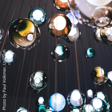 Glass spheres hang suspended on threads of steel.