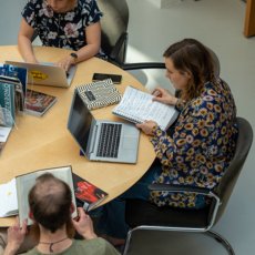 Drie studenten van de PThU werken aan een tafel in de bibliotheek.